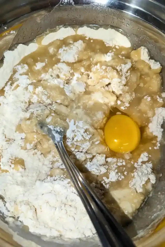 adding the egg to the flour mixture in a stainless steel bowl