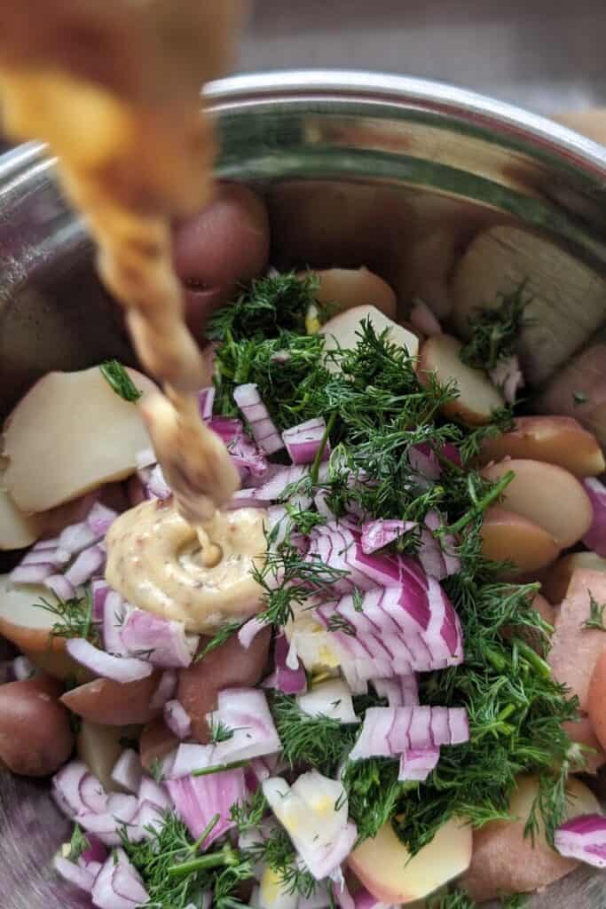 adding salad dressing to dillweed potato salad