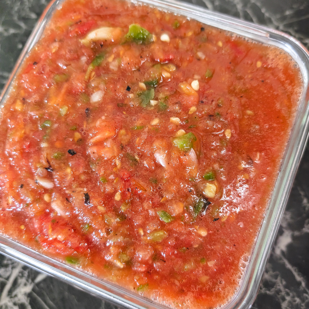 Fresh roasted tomato salsa with cilantro and garlic in a glass container.