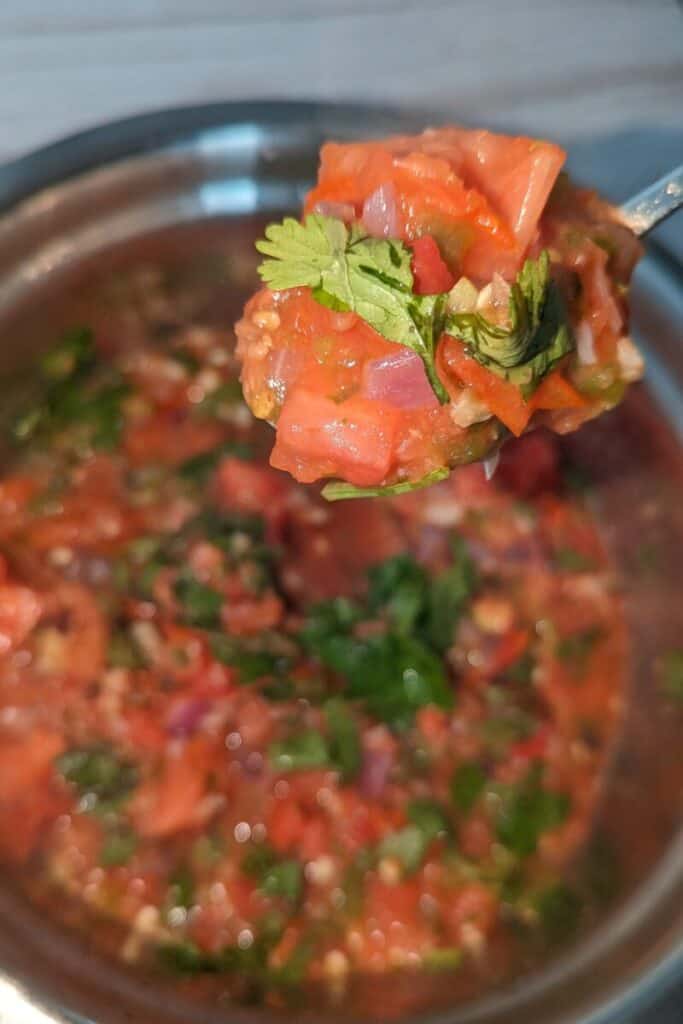 scooping chunky roasted tomato salsa