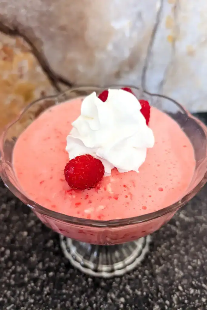 raspberry cheesecake salad dessert in dessert cup with cream and berries