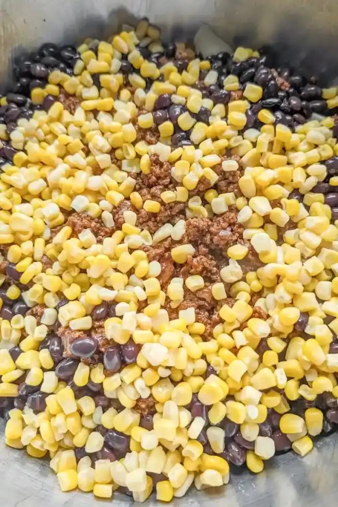 adding the canned sweet corn to taco salad