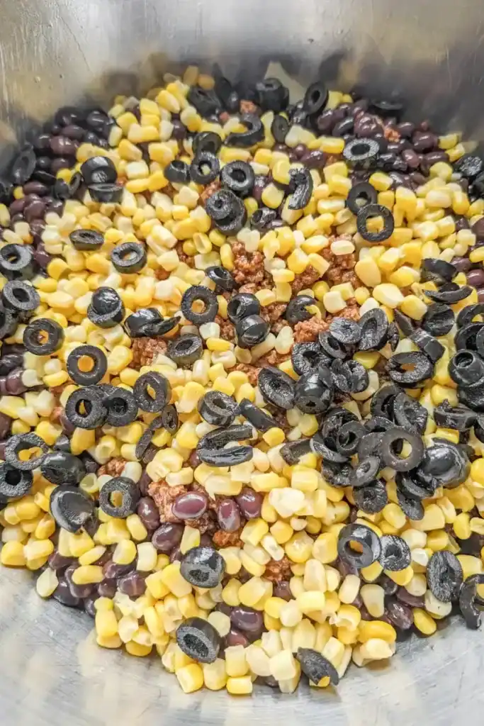adding the sliced black olives to the salad bowl