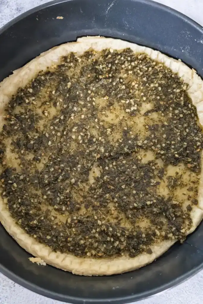 green basil pesto spread on the tart shell
