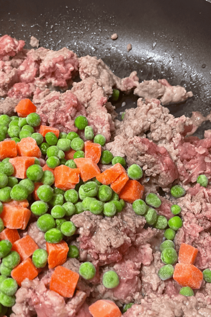 add frozen peas and carrots to ground beef and pork