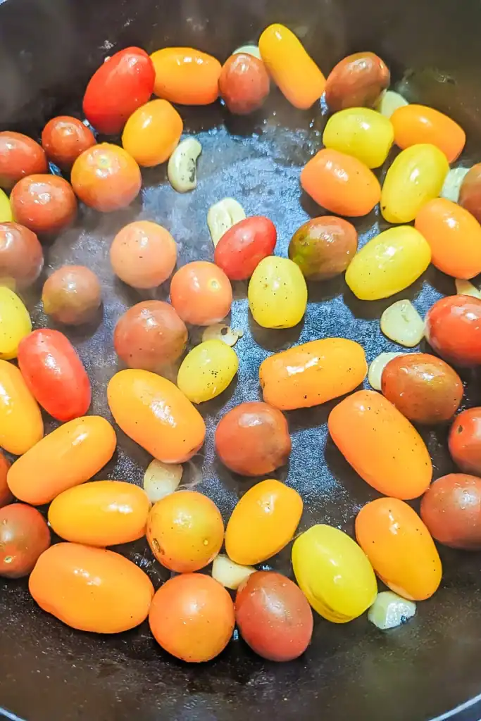 adding tomato to sauteed garlic