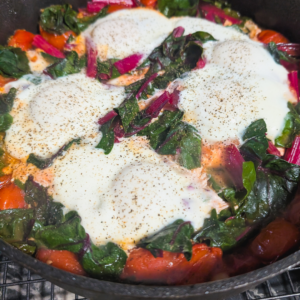 Eggs in Purgatory served with fresh vegetables and spices, perfect for a hearty breakfast or brunch.