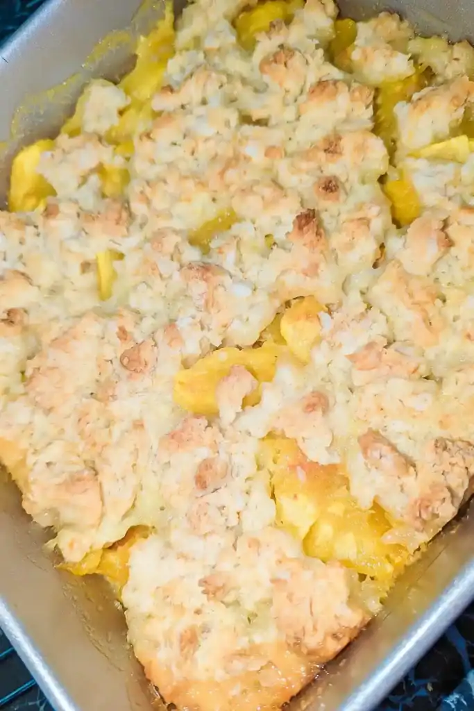top down look at the peach biscuit cobbler in baking pan on an angle
