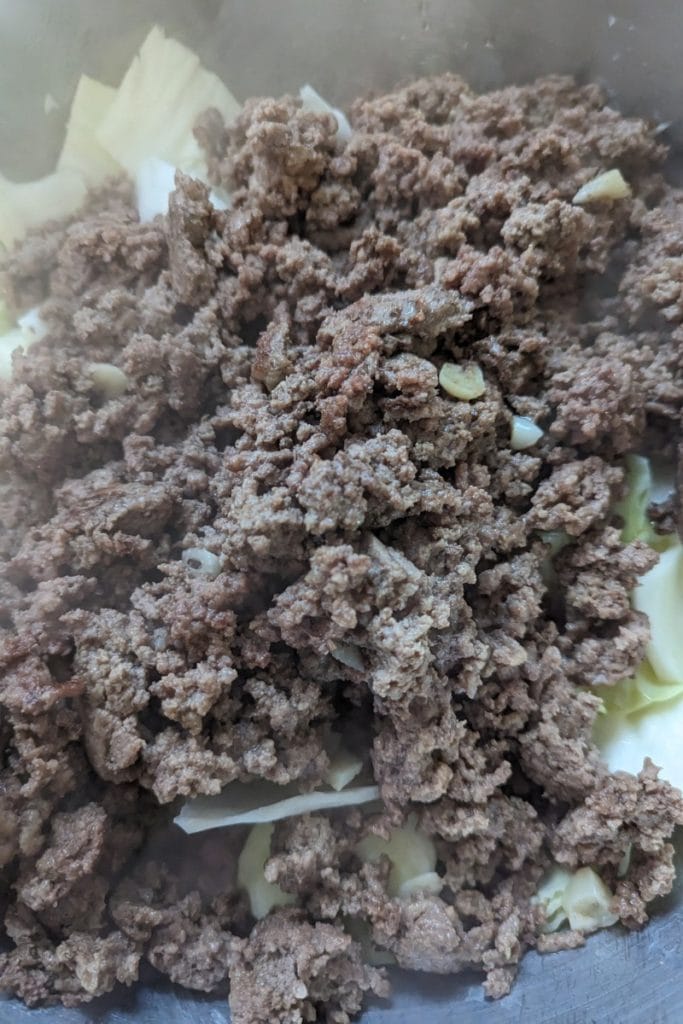 add browned ground beef to raw cabbage