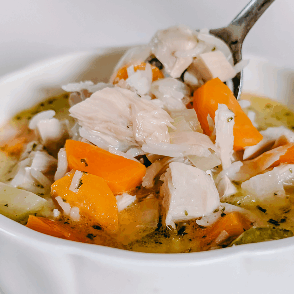 Comforting homemade chicken vegetable soup with carrots and herbs in a white bowl.