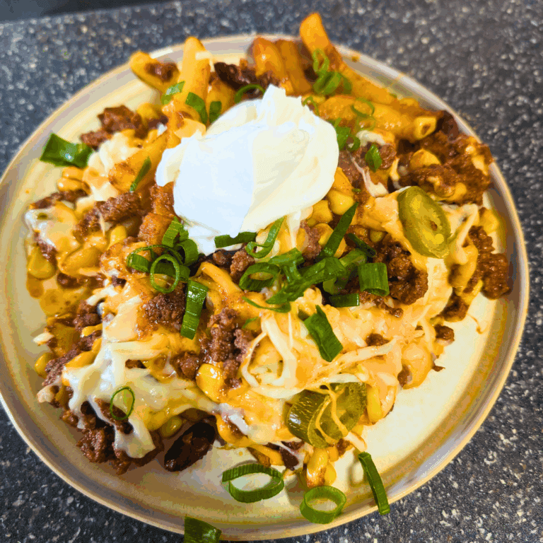 Cheesy beef casserole with jalapenos, sour cream, and green onions on a beige plate.