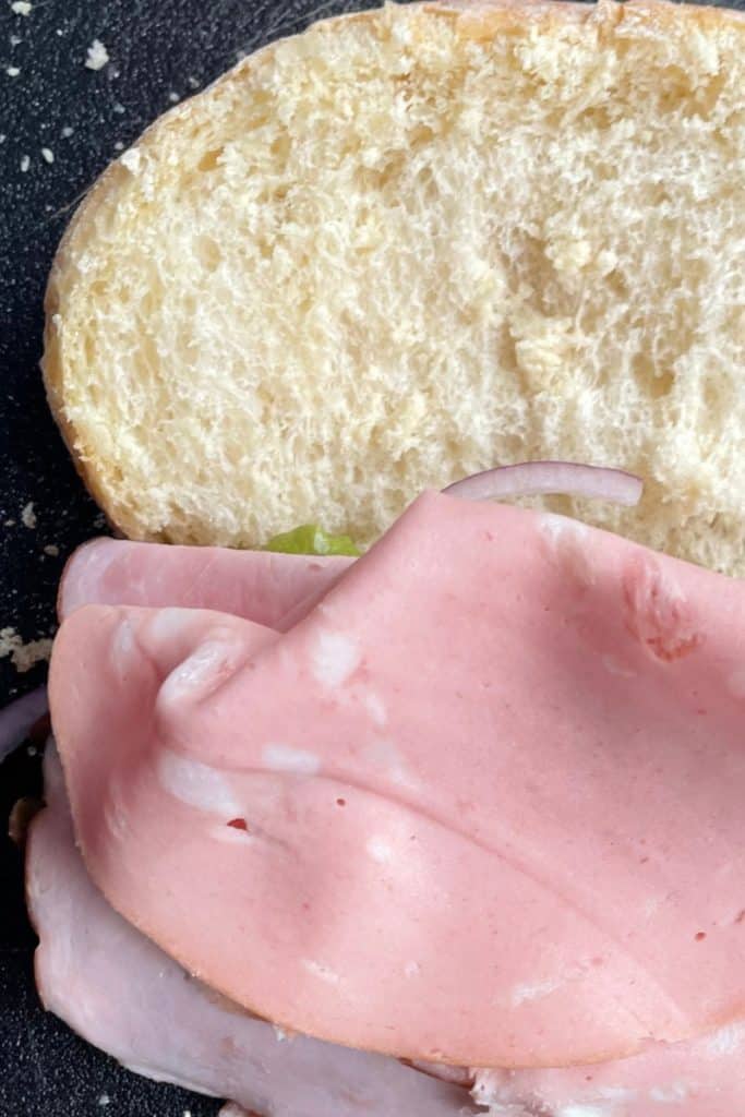 layering Mortadella onto the sliced ham