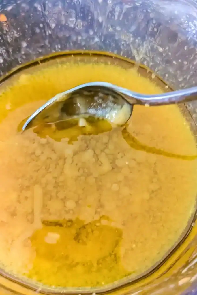 adding the dijon mustard to the honey vinaigrette and mixing well in a glass bowl dark background
