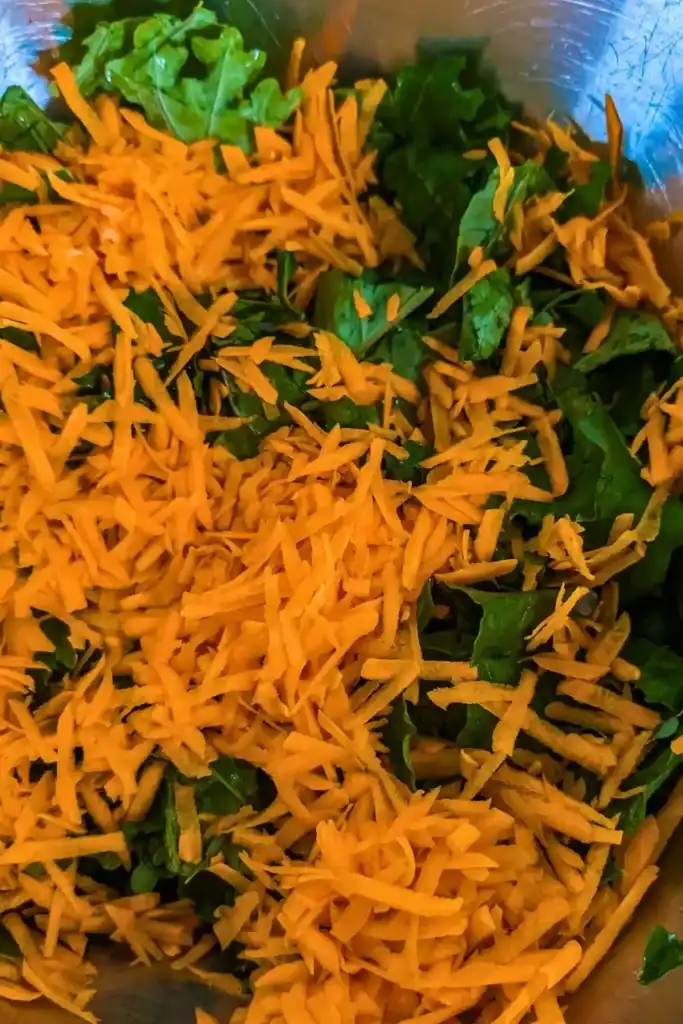 shredded raw carrots and kale in salad bowl