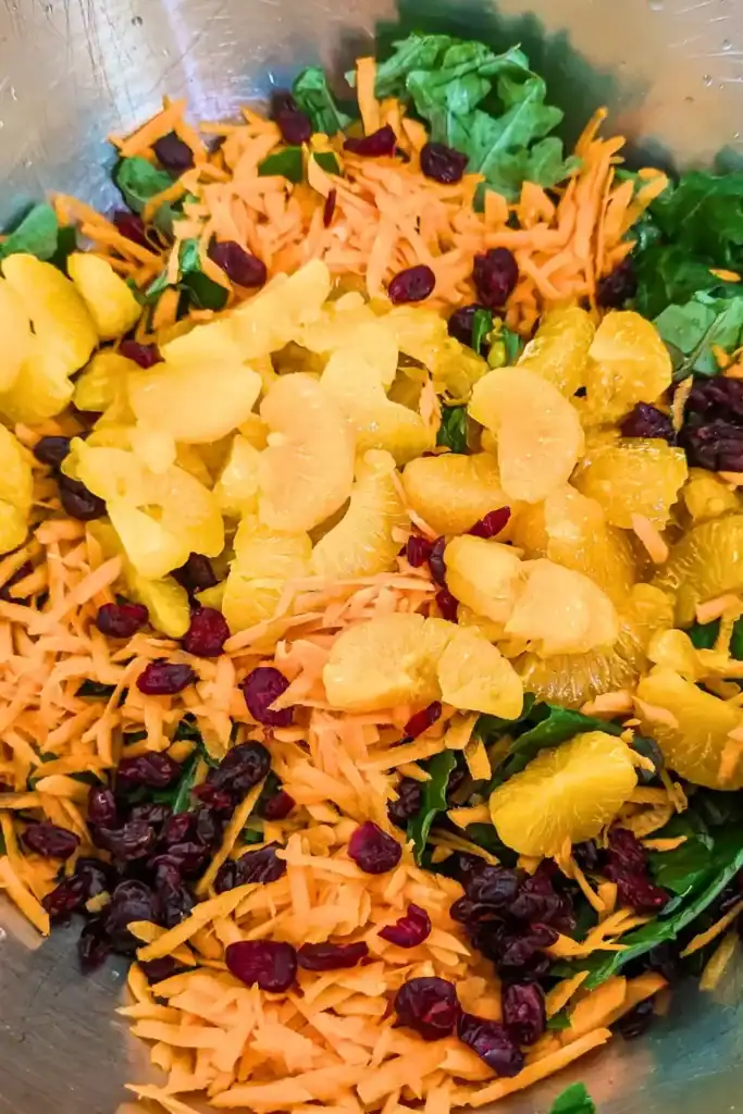 adding Mandarin orange segments to the kale salad in the salad bowl
