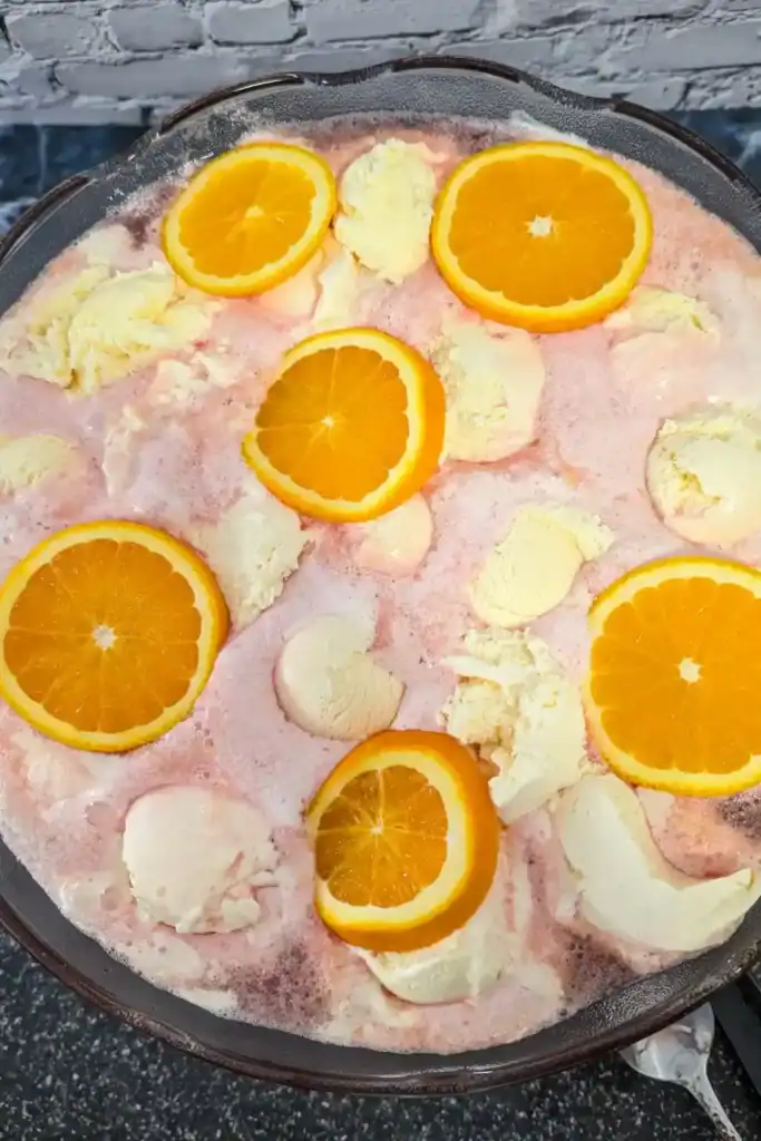 adding orange slices to surface of punch