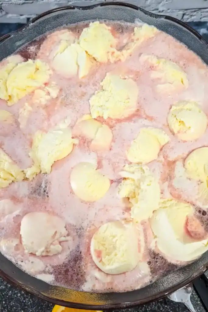 adding scoops of vanilla ice cream to surface of punch