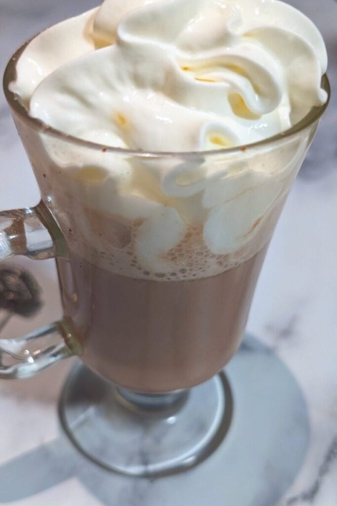 adding whipped cream to hot chocolate