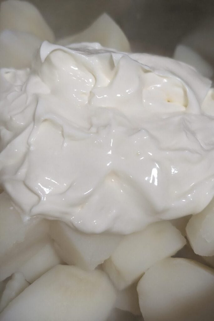 adding mayonnaise to cooked potatoes