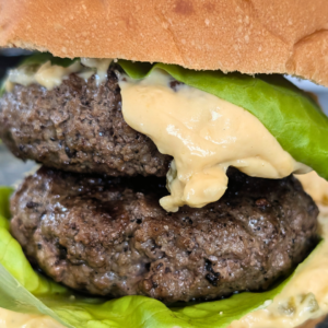 Delicious double cheeseburger cooked in a skillet with melted cheese and fresh greens, perfect for a.