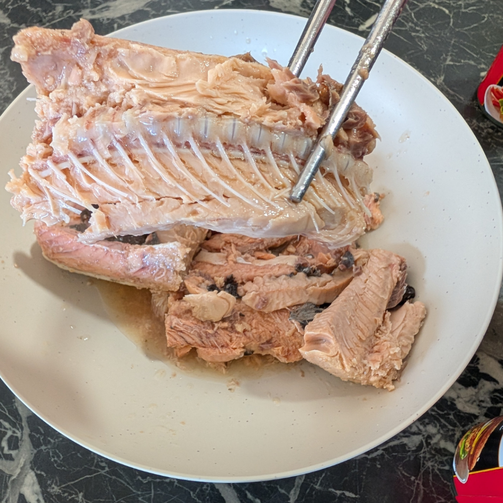 Fresh cooked fish head on a white plate, ready for soup or stew preparation.
