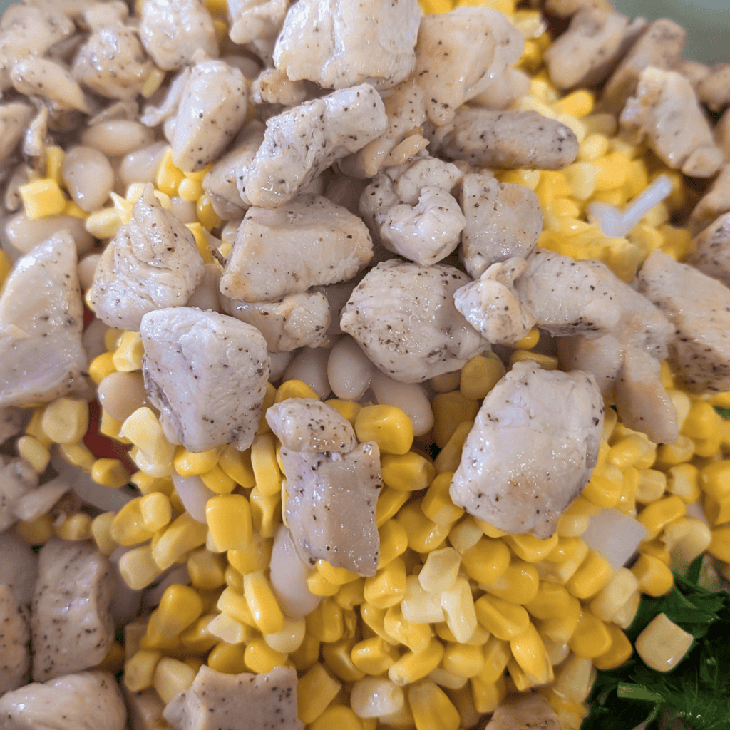 Close-up of grilled chicken pieces with corn and herbs for BBQ chicken wraps.