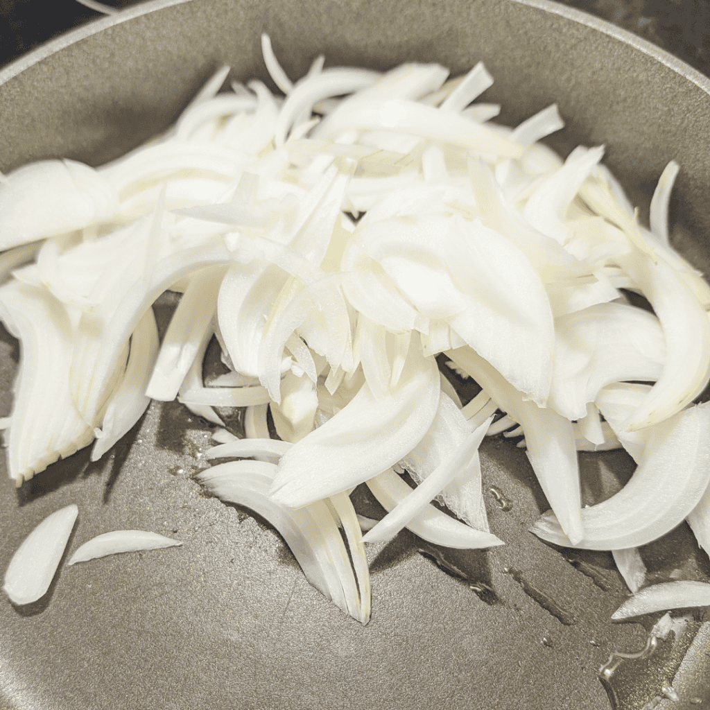 Sliced onions cooking in a pan for Japanese Gyudon beef rice bowl.