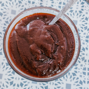 Rich chocolate BBQ sauce in a glass with a spoon.