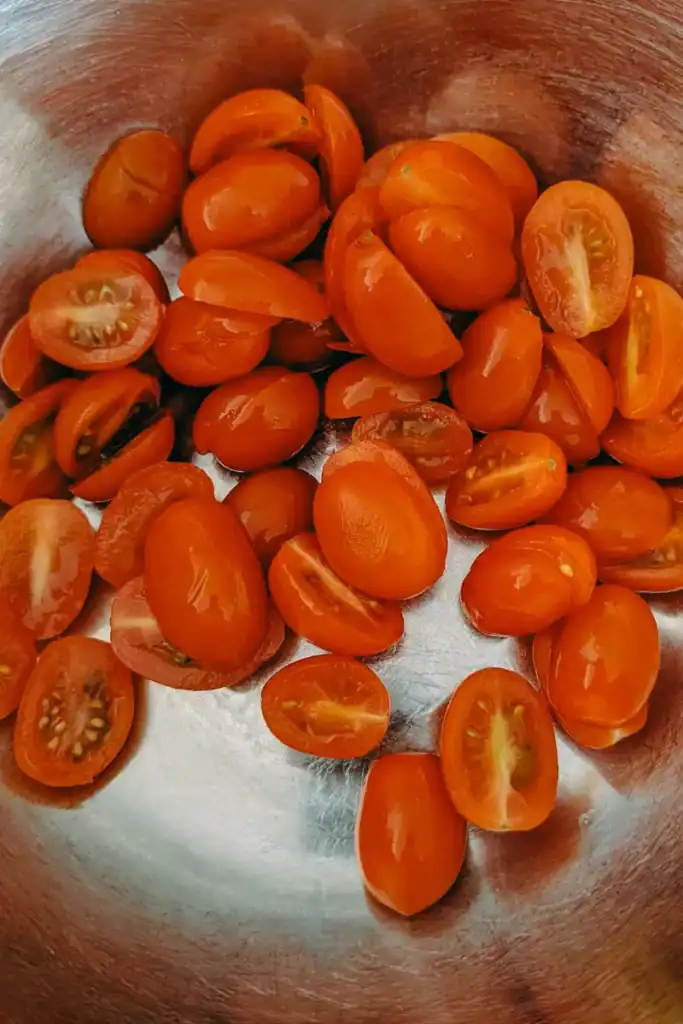 adding halved cherry tomatoes to salad bowl