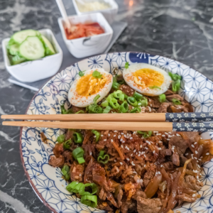 Delicious Japanese Gyudon beef rice bowl with boiled eggs and fresh vegetables.