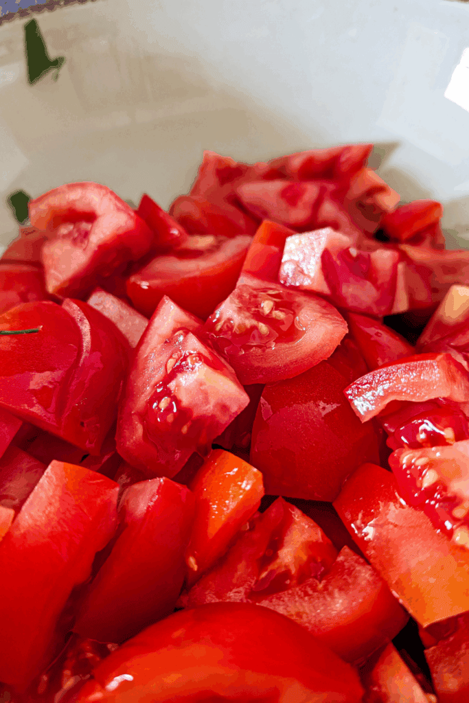 adding cut up fresh tomato to salad bowl