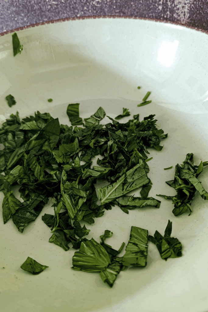 adding the chopped herbs to the bowl