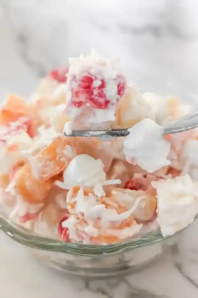 scooping up a cherry from ambrosia salad in bowl