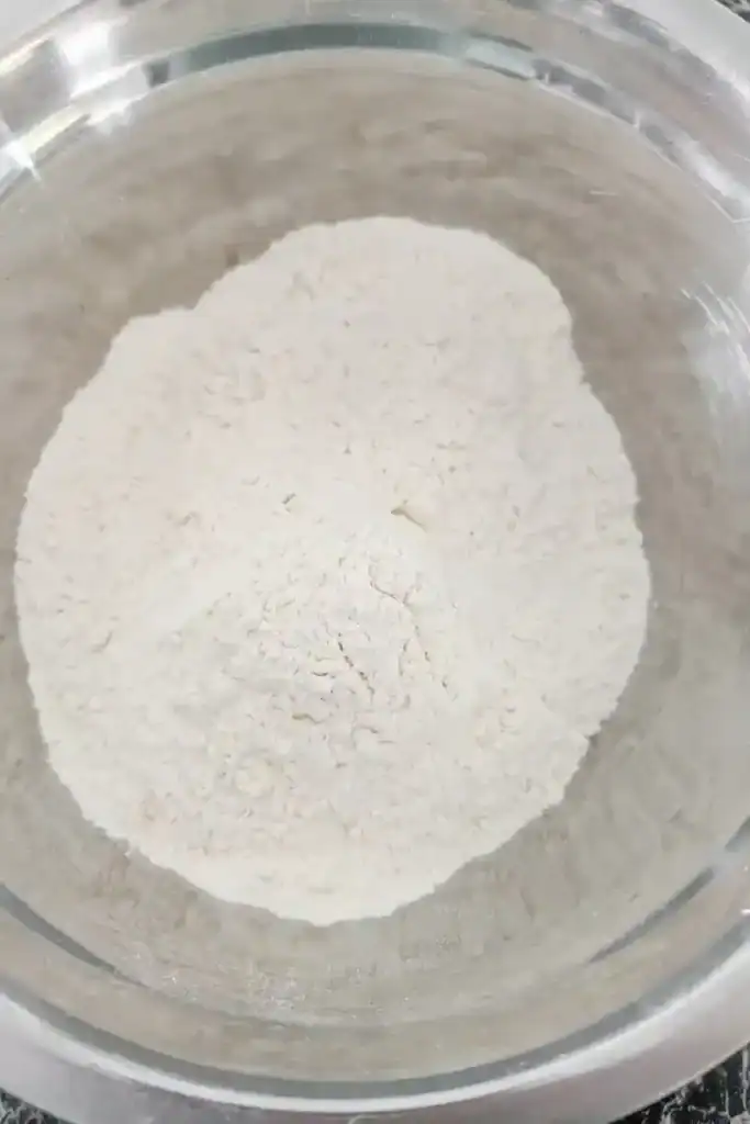 adding flour to mixing bowl for Jamaican patty dough