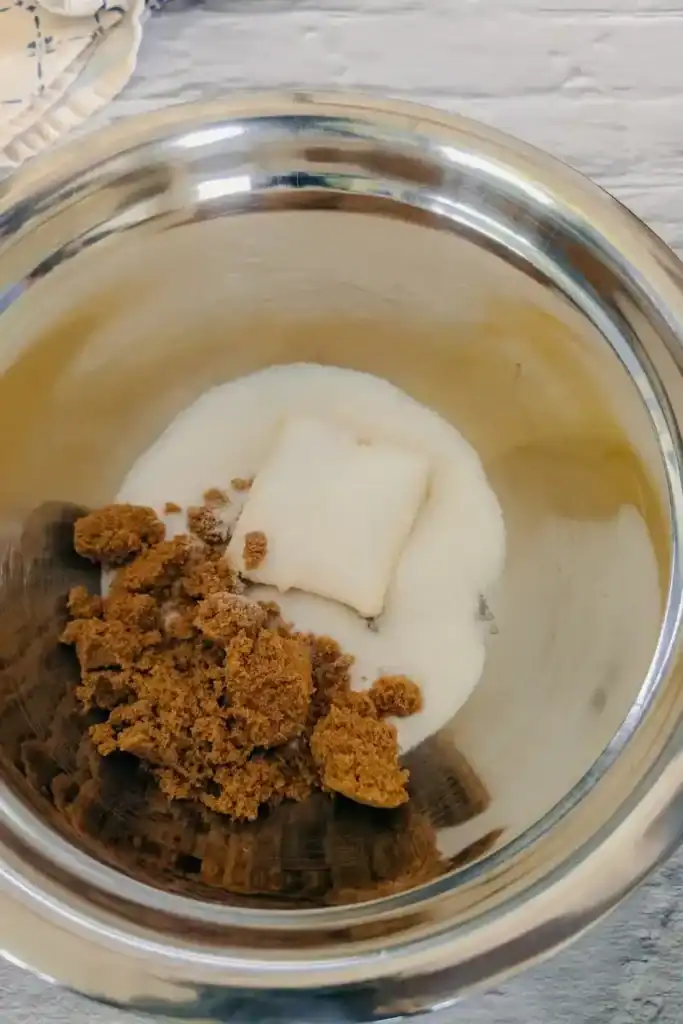 adding brown sugar to butter and white sugar in mixing bowl