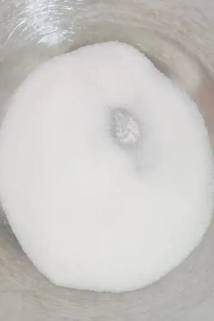 adding white sugar to stainless steel mixing bowl