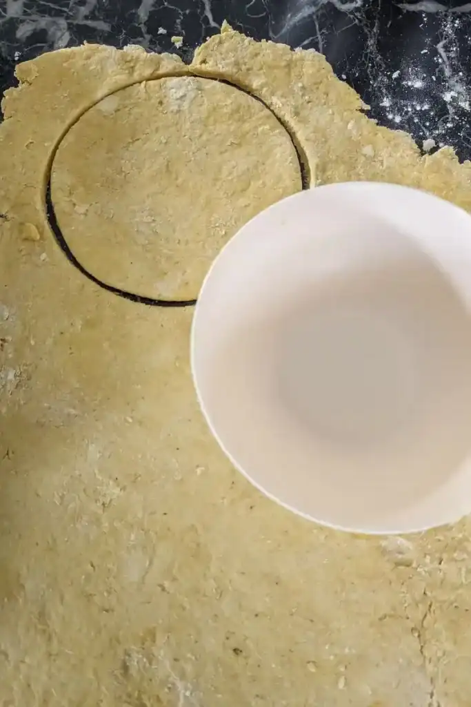 using small bowl to cut rolled patty dough into circles