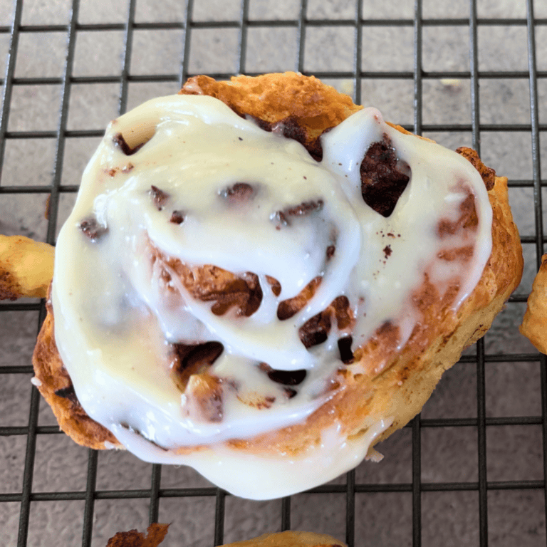 apple cinnamon biscuit roll with cream cheese frosting on wire rack