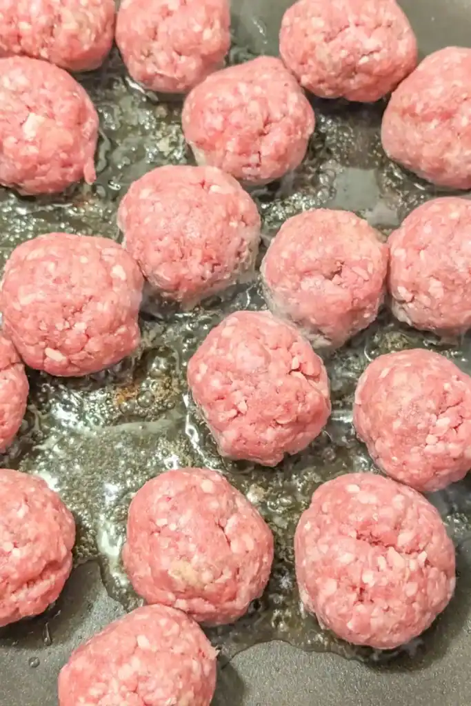 raw meatballs in non-stick frying heated with neutral oil