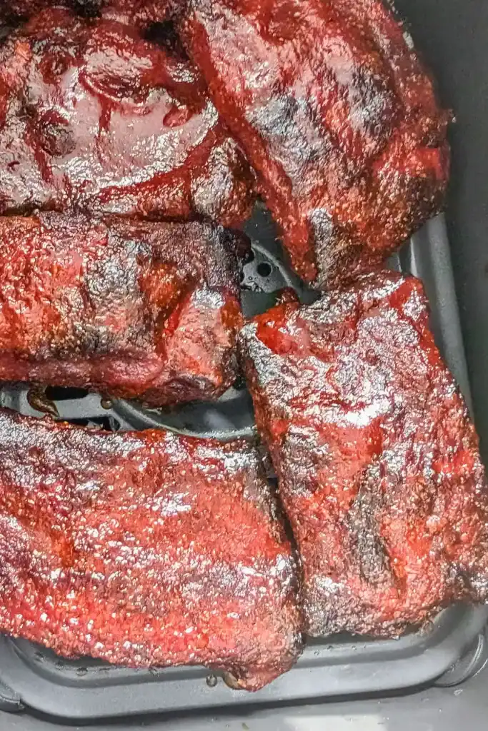 cooking the sauced ribs in the air fryer basket