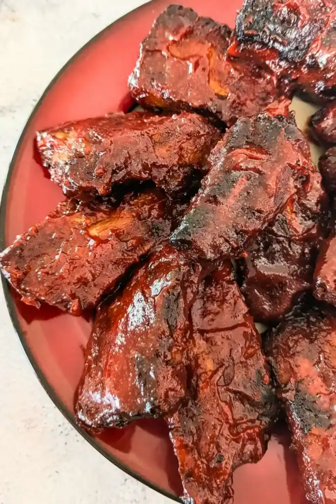 cooked sauced ribs from above on red rimmed plate