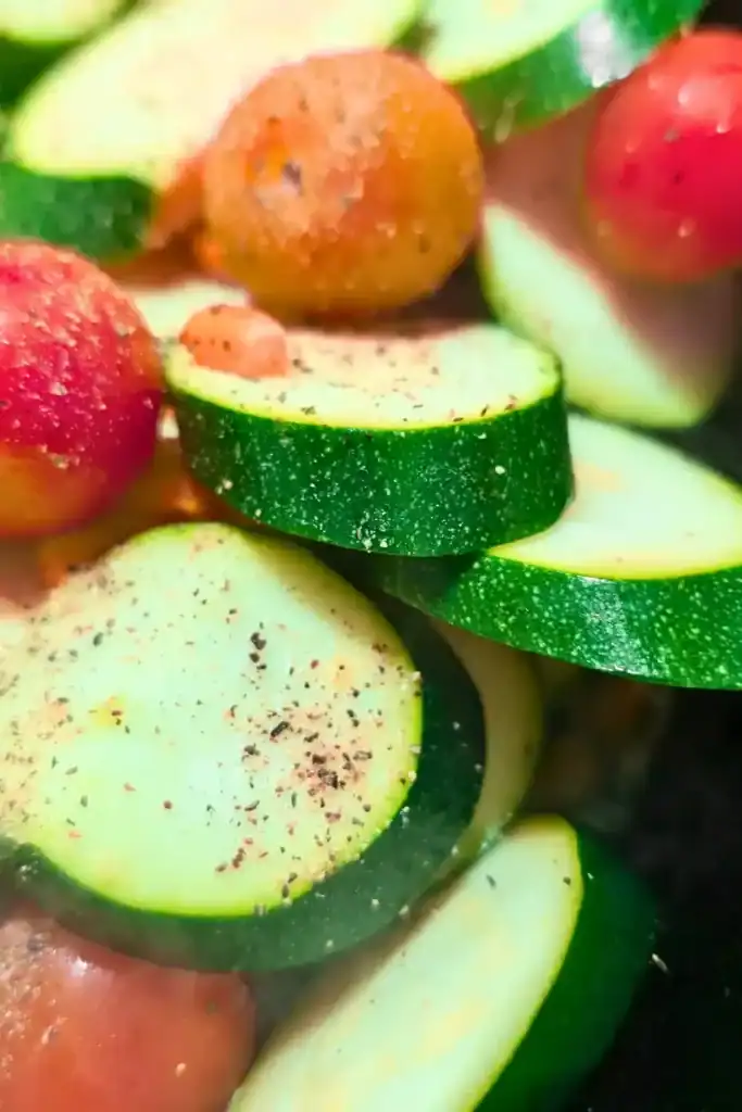 adding black pepper to vegetables in cast iron skillet
