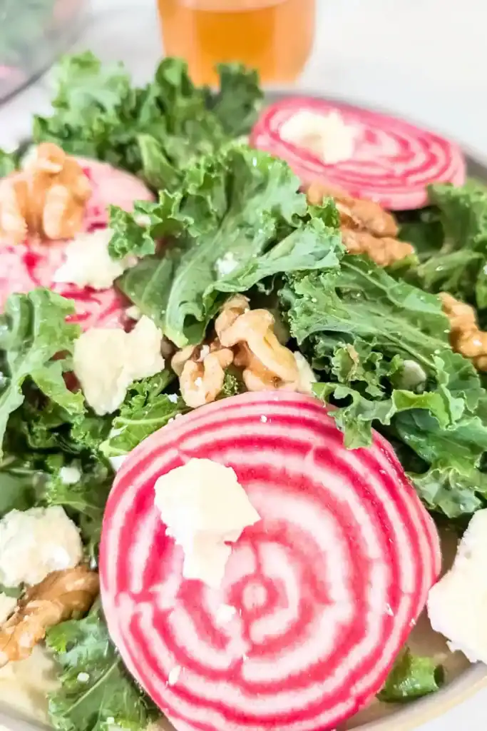 sweet beet kale salad on plate with small jar of dressing in background