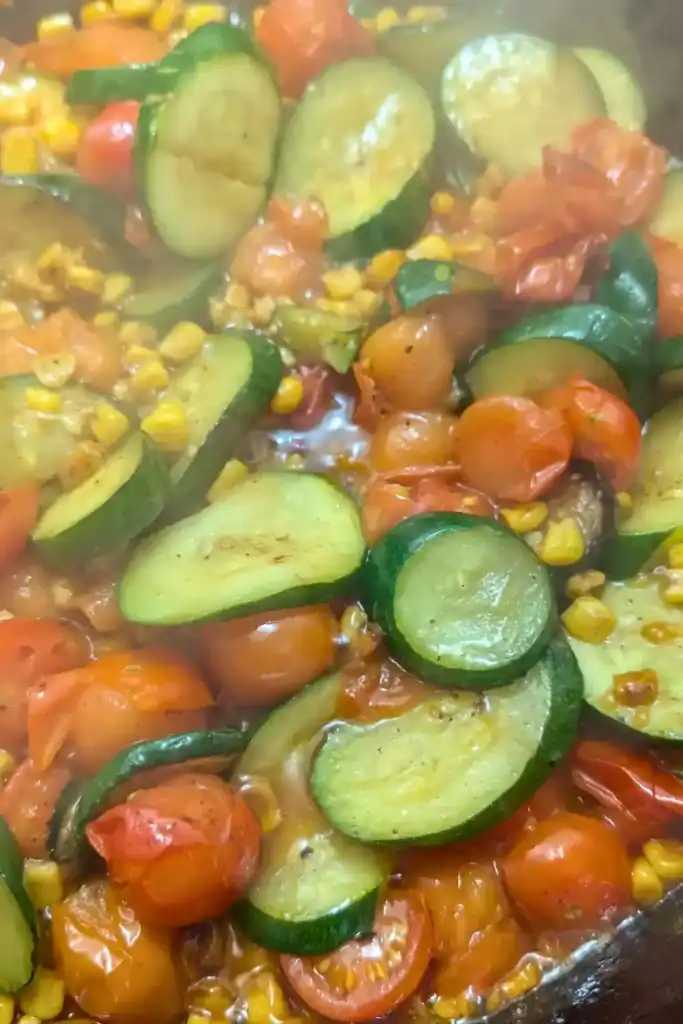 cooked vegetable side dish with tomato zucchini and corn in cast iron skillet