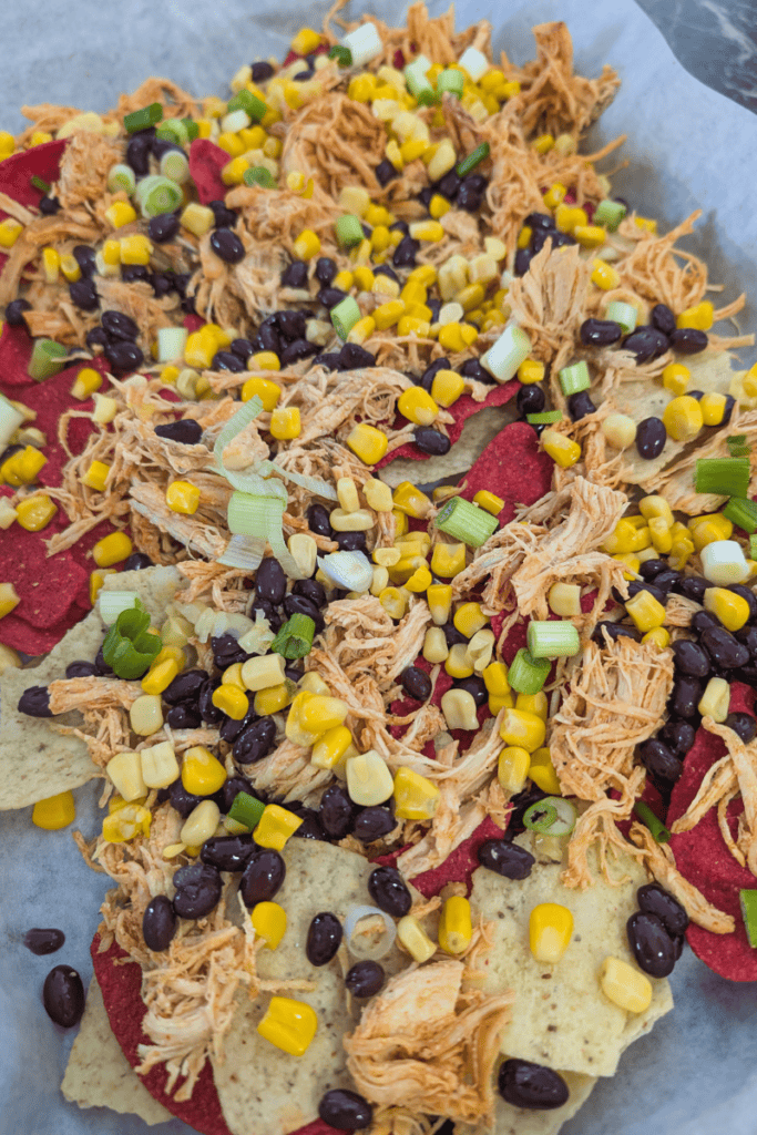 Delicious buffalo chicken nachos topped with cheese, black beans, and fresh vegetables. Perfect for.