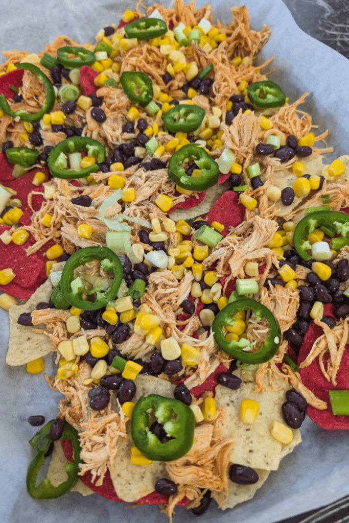 Delicious buffalo chicken nachos topped with jalapeños, black beans, and corn for a spicy, savory sn.