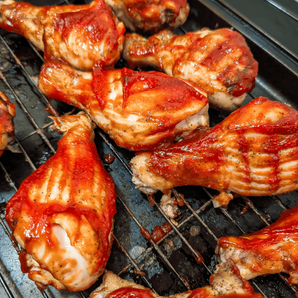 Juicy grilled chicken drumsticks glazed with smoky BBQ sauce on a grill rack.