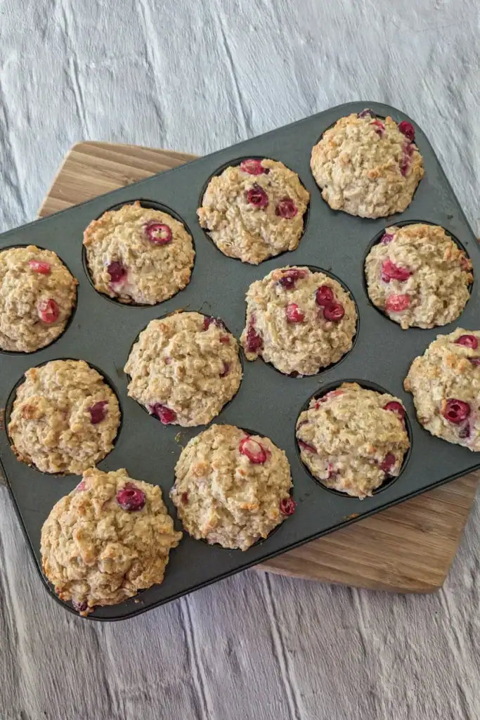 the muffins in muffin pan on wooden cutting board cooling