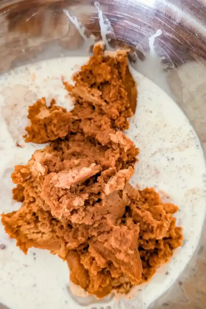 adding real pumpkin puree to the pie filling in mixing bowl