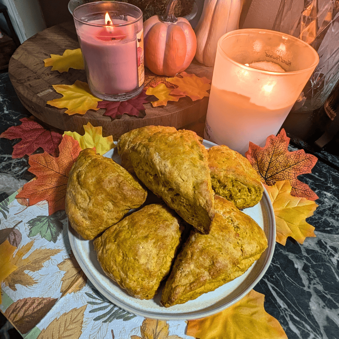 pumpkin spice scones piled on plate with candles and fall decor behind